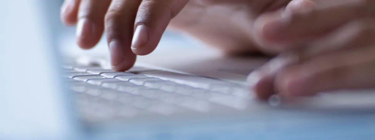 Hands typing on a laptop keyboard